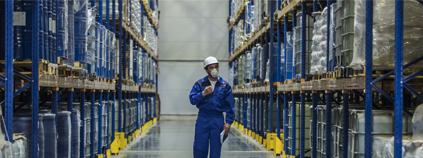 Man walks through a chemical storage warehouse with mask and PPE