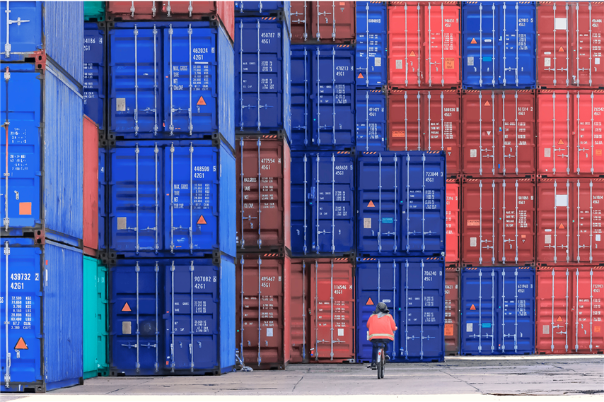 Port Worker Cycles Through The Container Stacks