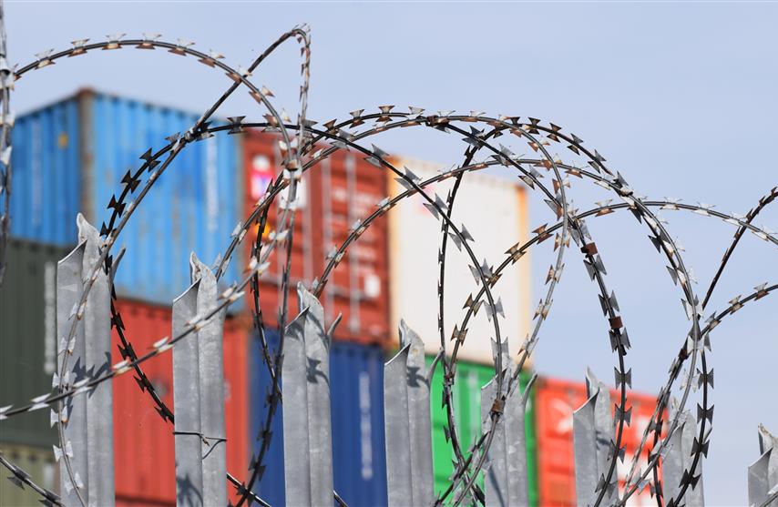 Southampton, UK. April 22 2019. Freight cargo shipping containers behind secure fencing and barbed wire at one of the UK's busiest ports on the South Coast.