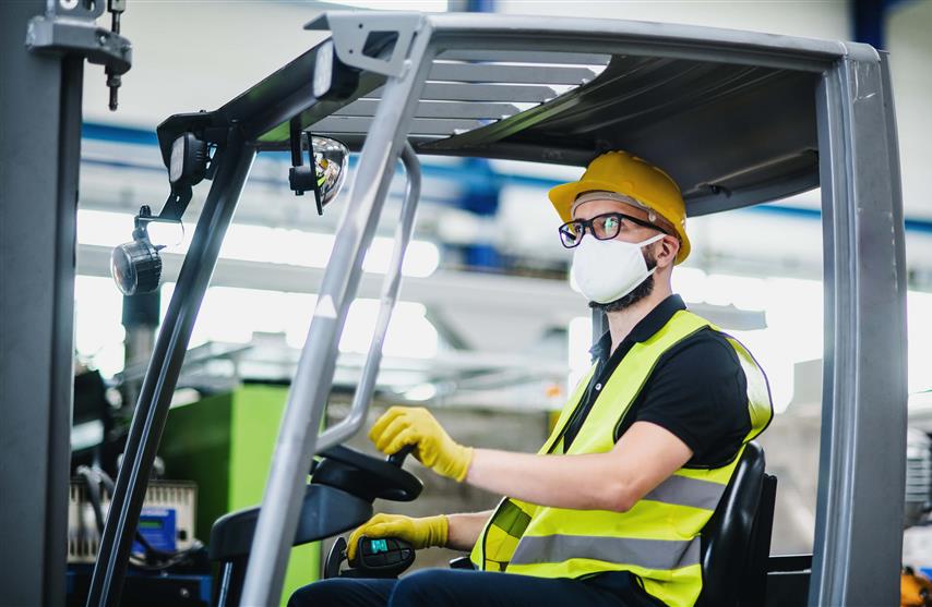 man driving forklift with protective mask