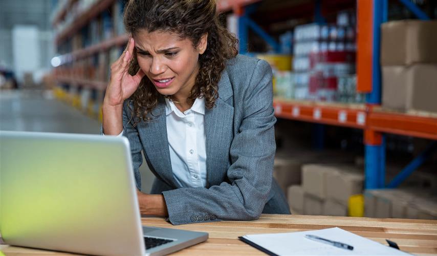 woman stressed looking at laptop in warehouse